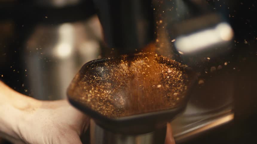 A person pouring brown dust from a machine inside a container