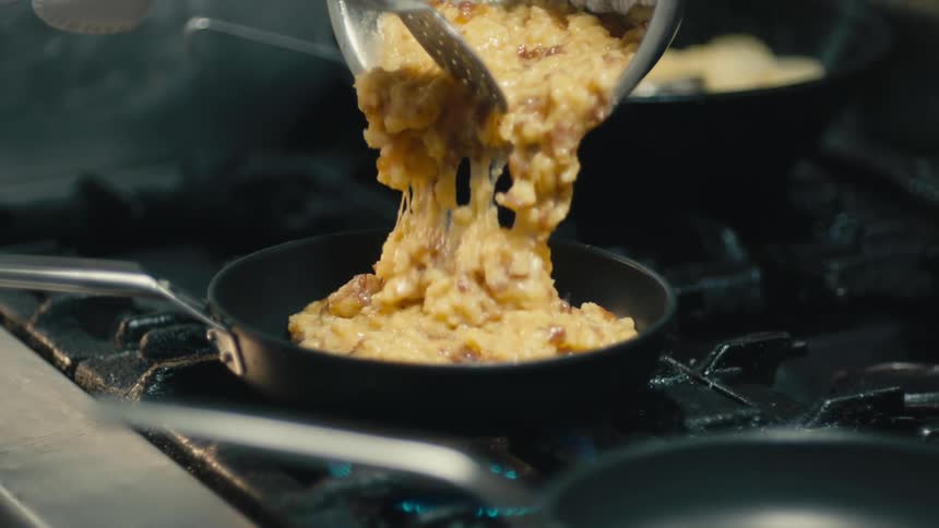Food is being poured into a pan on the stove