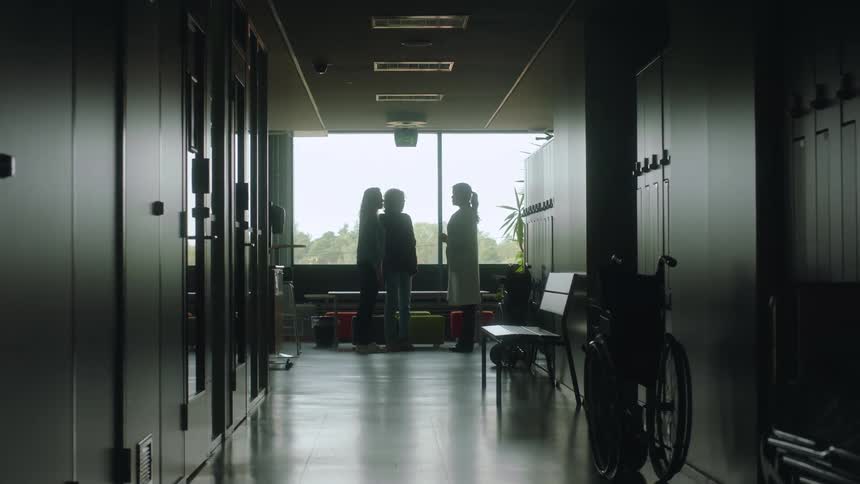 A doctor walks down a hospital hallway to meet with family of a patient