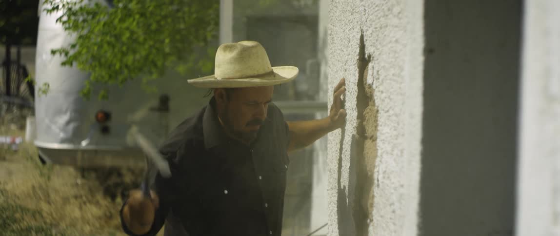 Man uses hammer to demolish exterior building wall