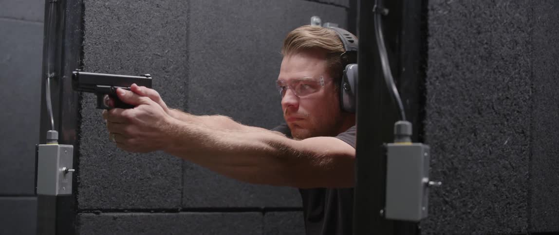 Man wearing safety earmuffs shoots a gun