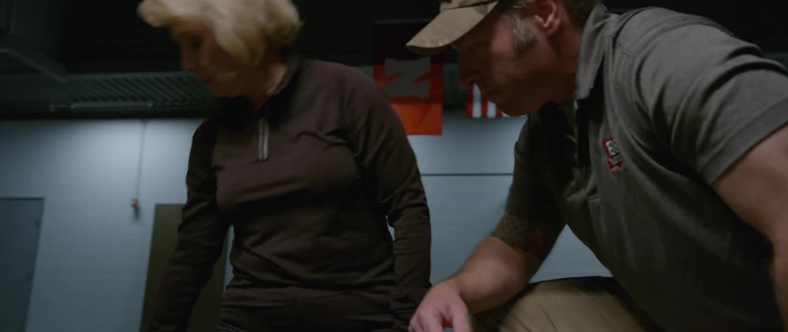 An older woman ties a tourniquet on a man's leg