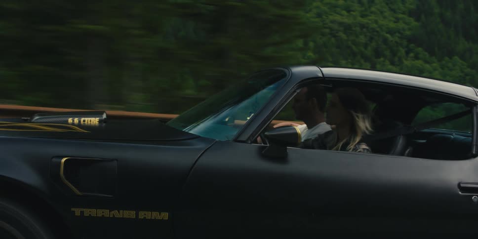 People drive their sports car on the highway by the mountains