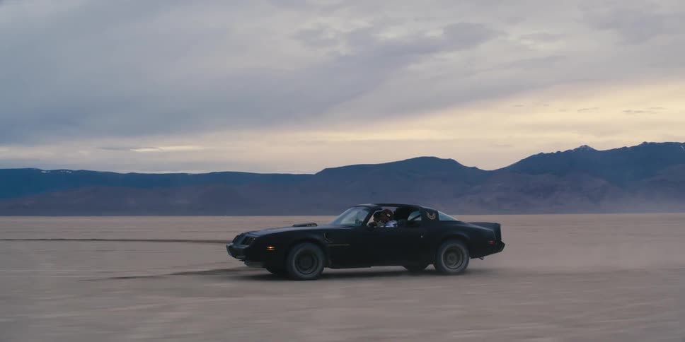 A t top trans am travels across packed sand kicking up dust