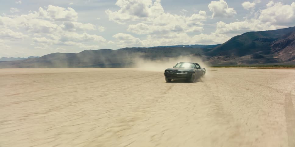 Sports car kicking up dust on the desert plains near the mountains