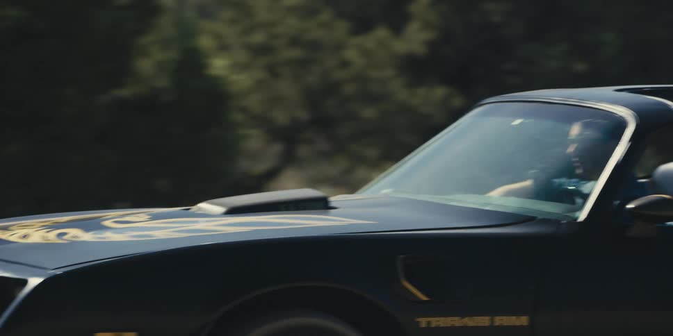 A woman drives a vintage sports car through the desert