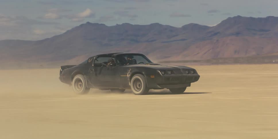 A car speeds on the desert sand