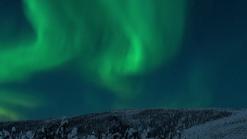 The northern lights flow above the mountain