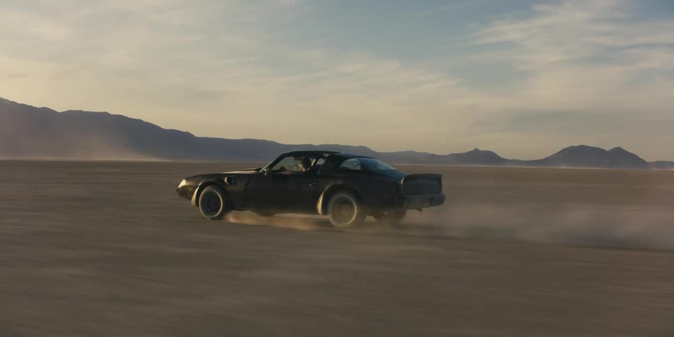 A car is speeding in the desert with two people