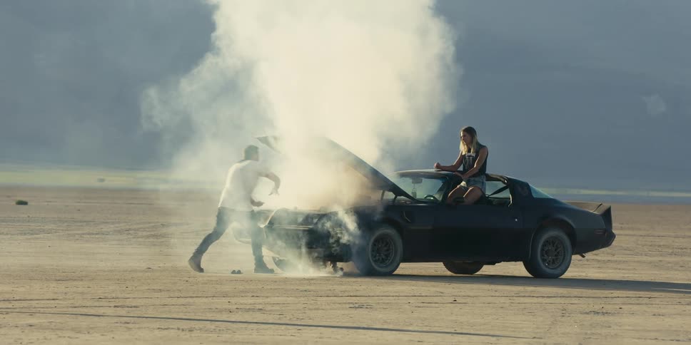 Smoke flows from the broken down vehicle as two people argue