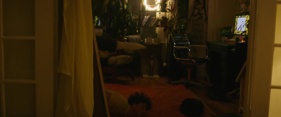 Man with shirt and black pants does dance next to desktop in dim lit room