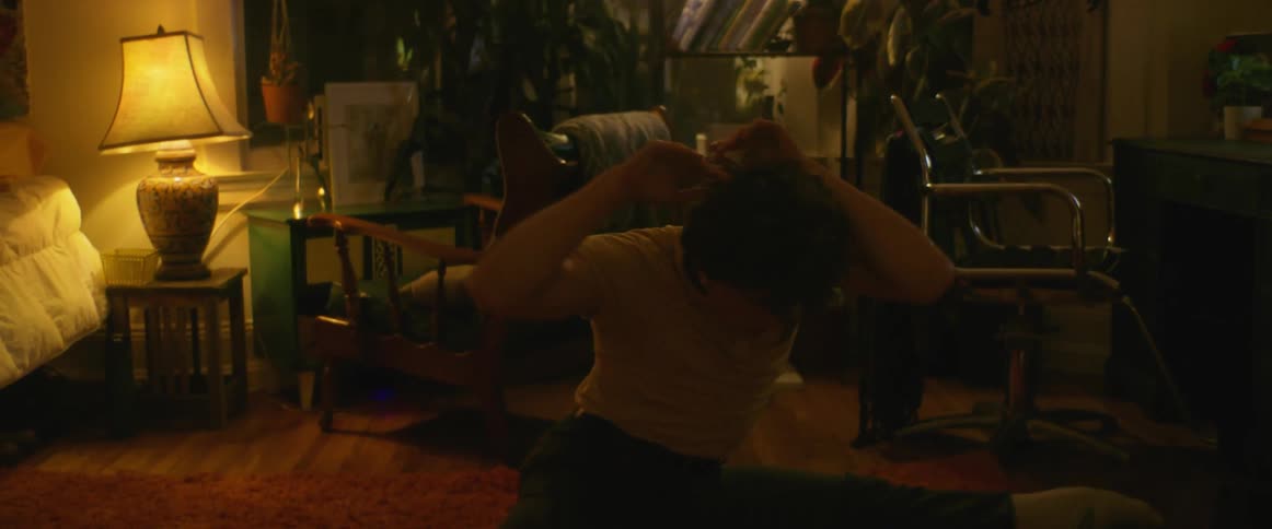 A man is performing a modern dance on the floor of his bedroom at night