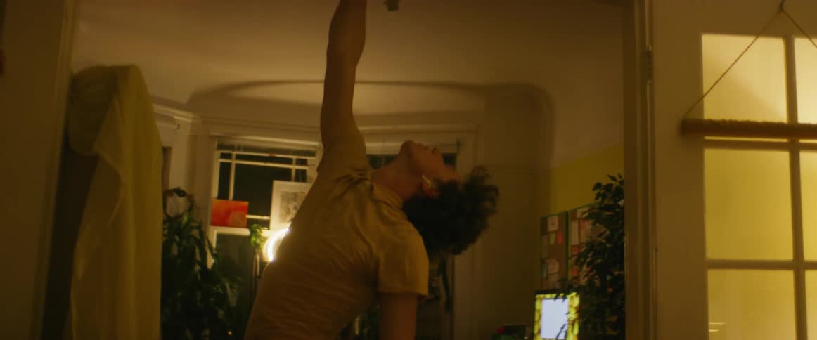 Young man dancing around a room in an apartment at night
