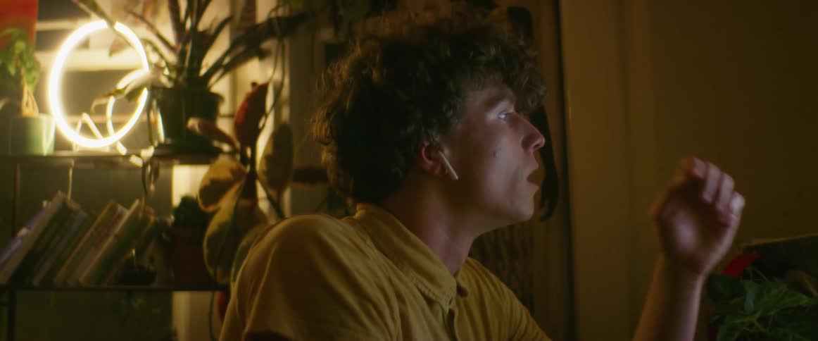 A man puts his airpods in then leans forward to look at his computer sighing deeply