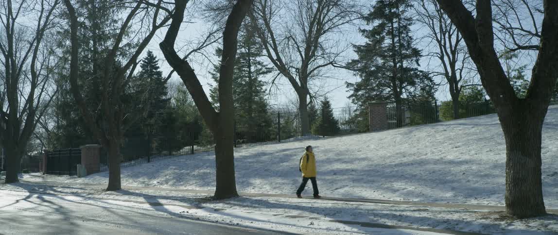 A boy is walking along a sidewalk