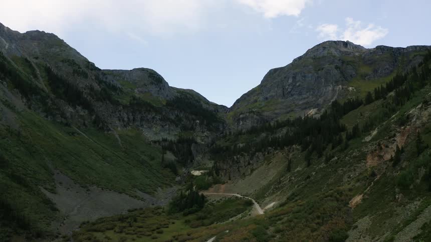 A road winding in a canyon between tall mountains with trees