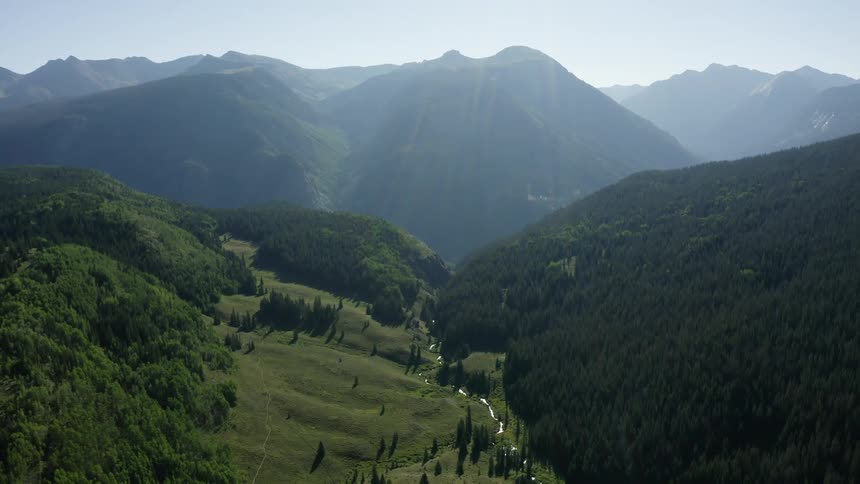 A valley with a river with a mountain range the sky and clouds in the background