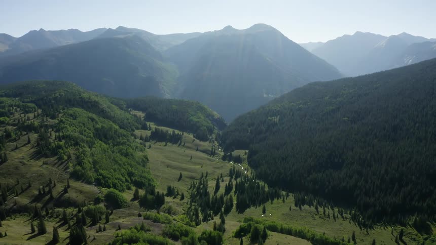 A valley with a river with a mountain range the sky and clouds in the background