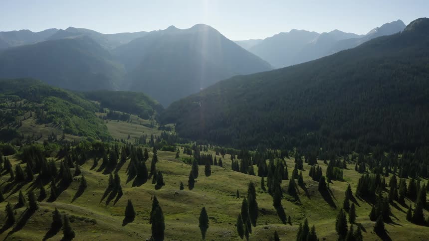 A landscape with trees and hills with a mountain range the sky and clouds in the background