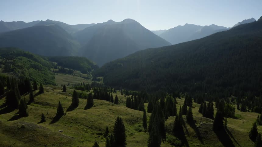 A landscape with trees and hills with a mountain range the sky and clouds in the background