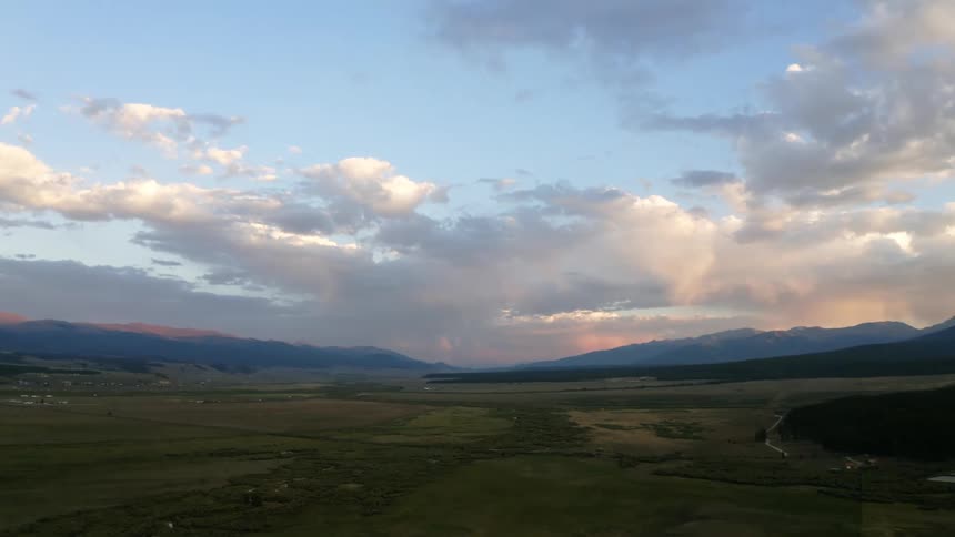 An aerial view of rural farmland with mountains in the background on a cloudy evening