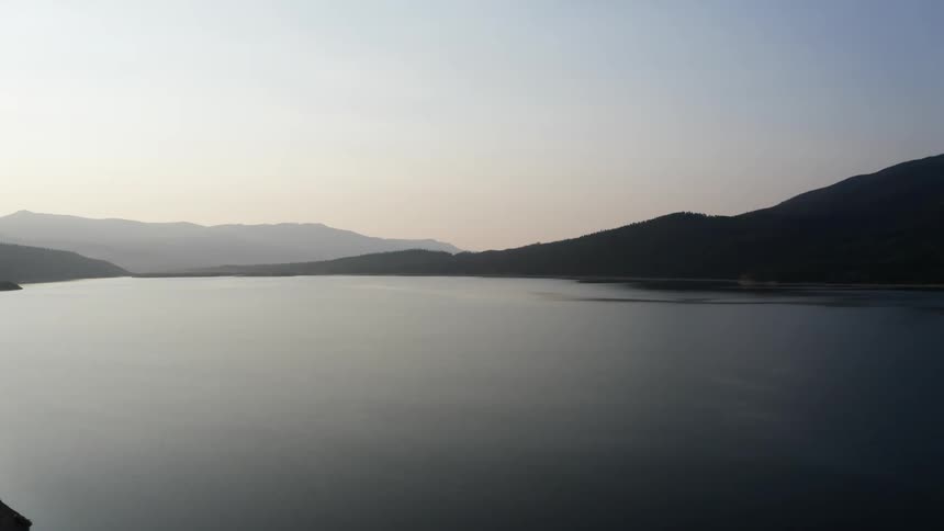 View of lake and mountains silhouetted against the sky at dusk