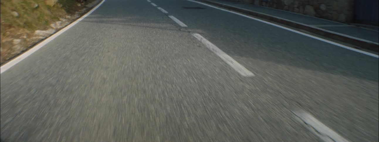 A vehicle traveling on a rural paved road on an autumn day