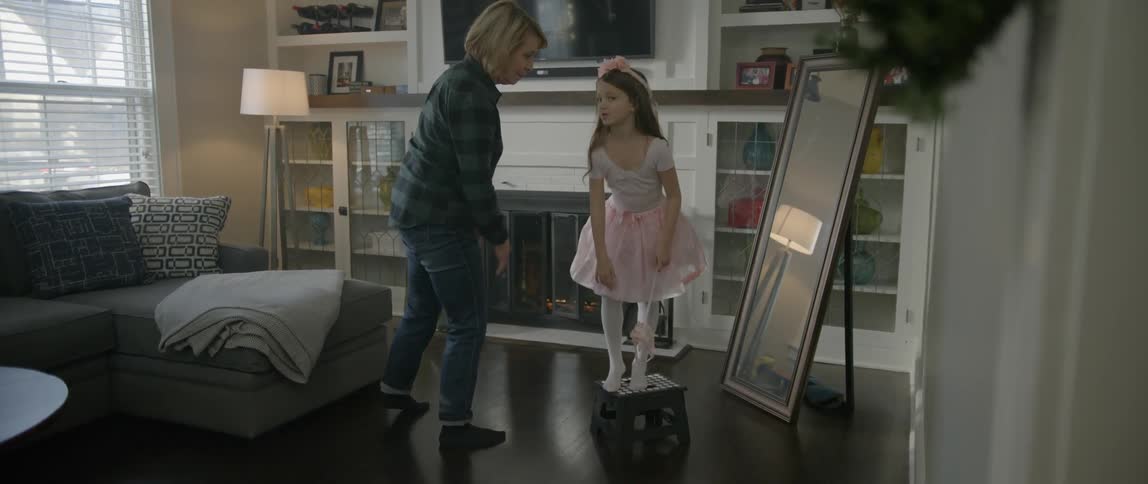 A girl is dressed in a costume as her mom helps her