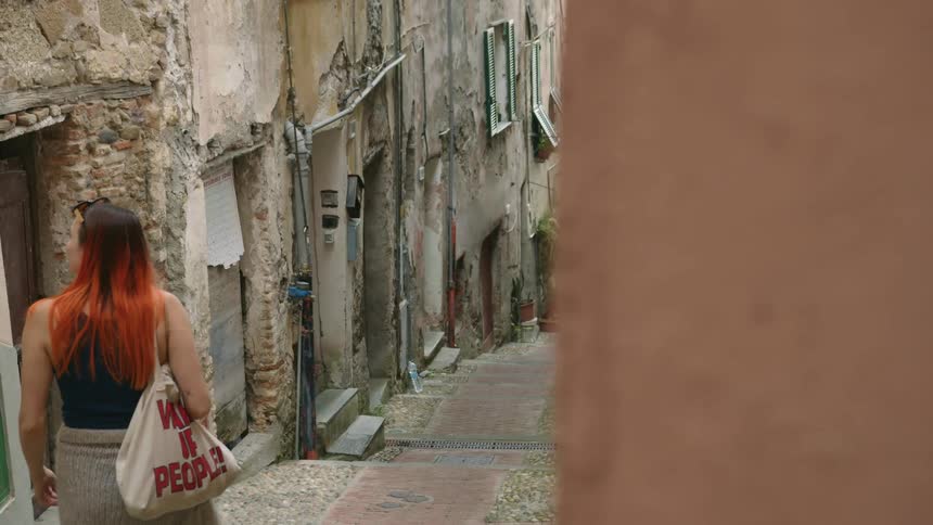 A woman walking alone in a city with old stone buildings