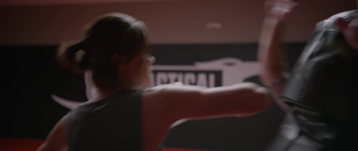 A woman is sparring in a gym