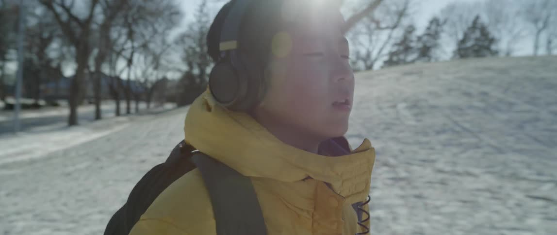 A boy in a yellow jacket stops in front of a group of three boys