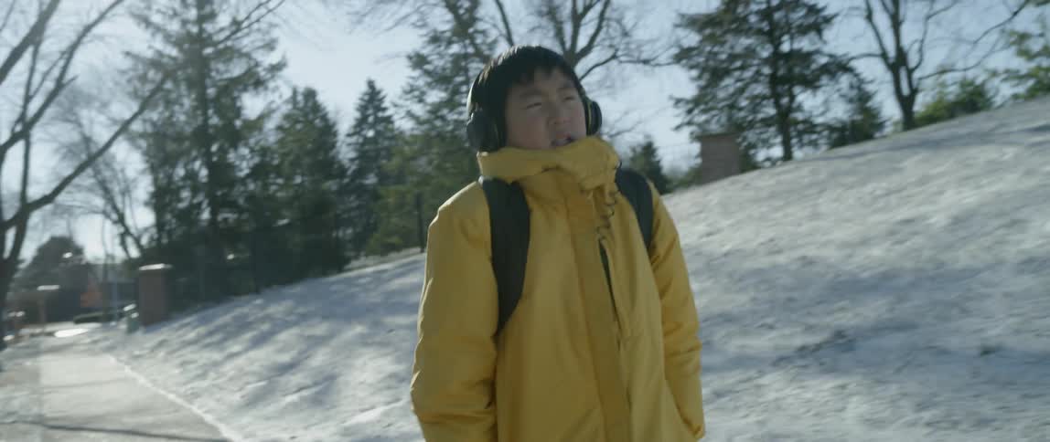 A boy is walking along a sidewalk