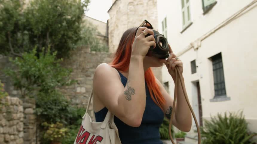 A woman taking photos with a camera outdoors