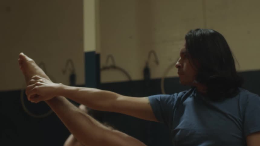 A man with long dark hair is practicing aerobics