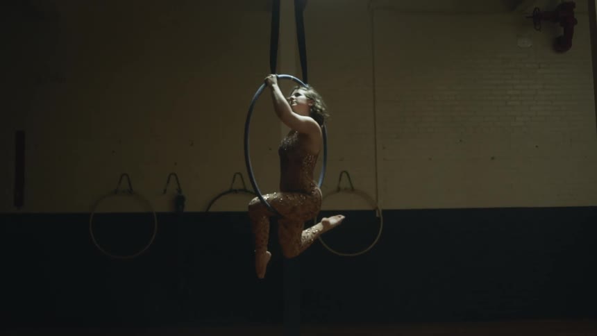 Female acrobat rotates while performing on floating hoop in practice studio