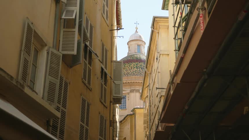 Ornate domed church is visible at end of alley behind apartment building