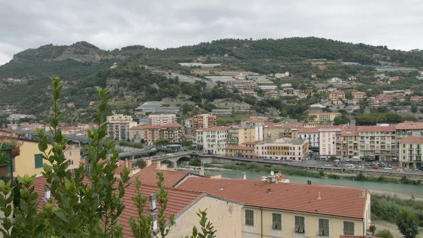 Buildings next to a river with bridges with hills the sky and clouds in the background