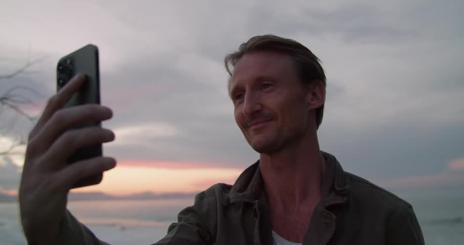 A man says goodbye to someone on the phone while on the beach