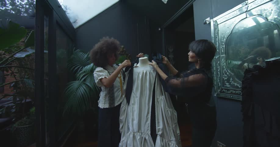 Two women are working on designing an outfit in a shop on an overcast day