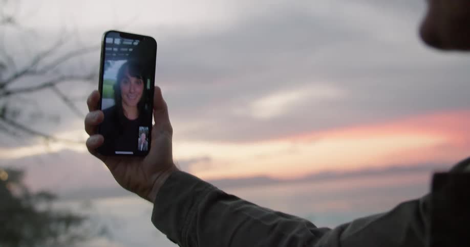 A man and woman chatting via video call on smartphones while outdoors