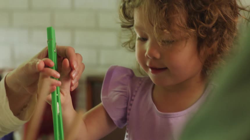 A mother hands her daughter chopsticks designed for children during a meal in their dining room during the day