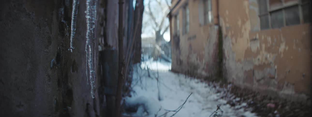 Icicles drip as they melt into snow between two buildings