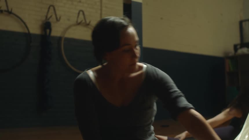 A woman stretching while sitting on the floor in a fitness room