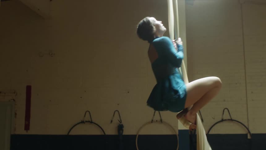 A woman climbing fabric to do acrobatic dancing