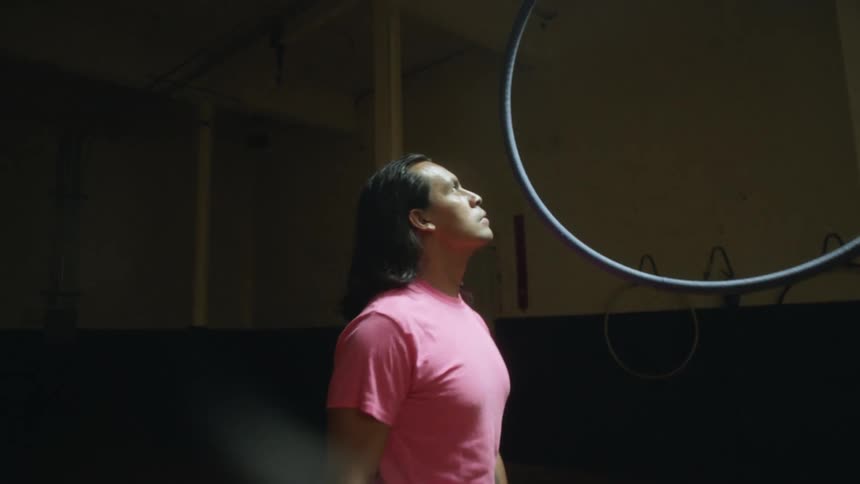 A man standing next to a suspended hoop in a dance studio