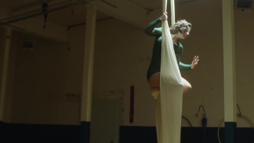 A female acrobat doing poses on a suspended piece of fabric
