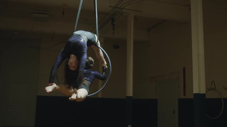 Two female acrobats performing tricks on a suspended hoop