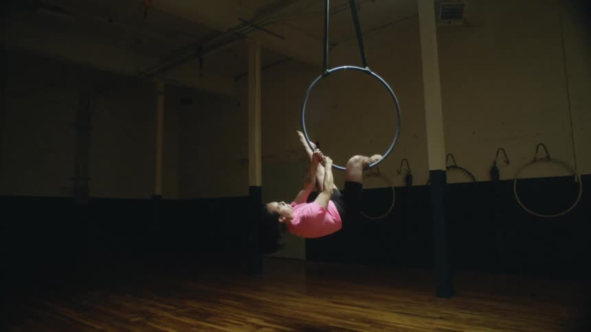 A man is hanging from the ring in the gym