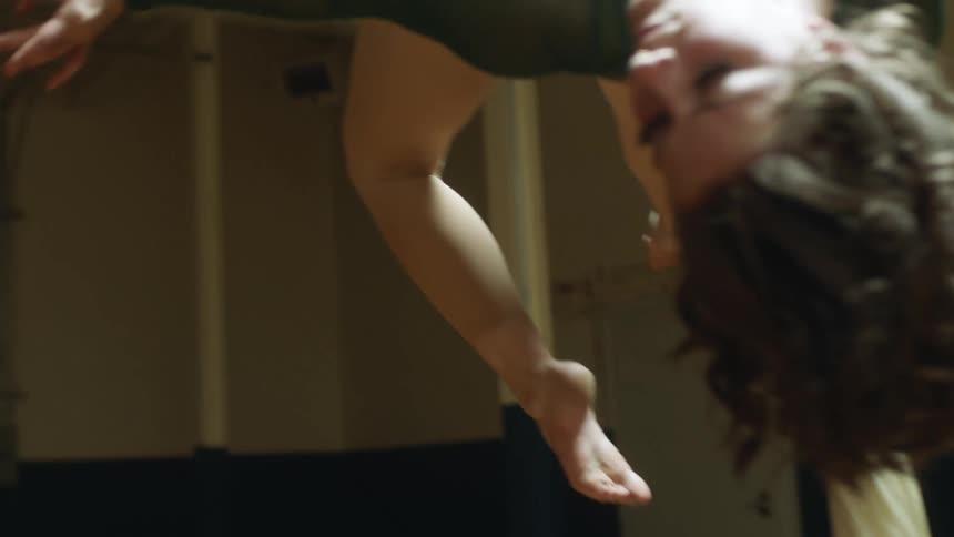 A female acrobat dangling from a suspended piece of fabric