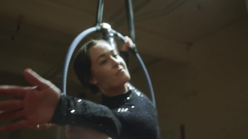 Two female acrobats are wearing leotards and posing in a hanging ring